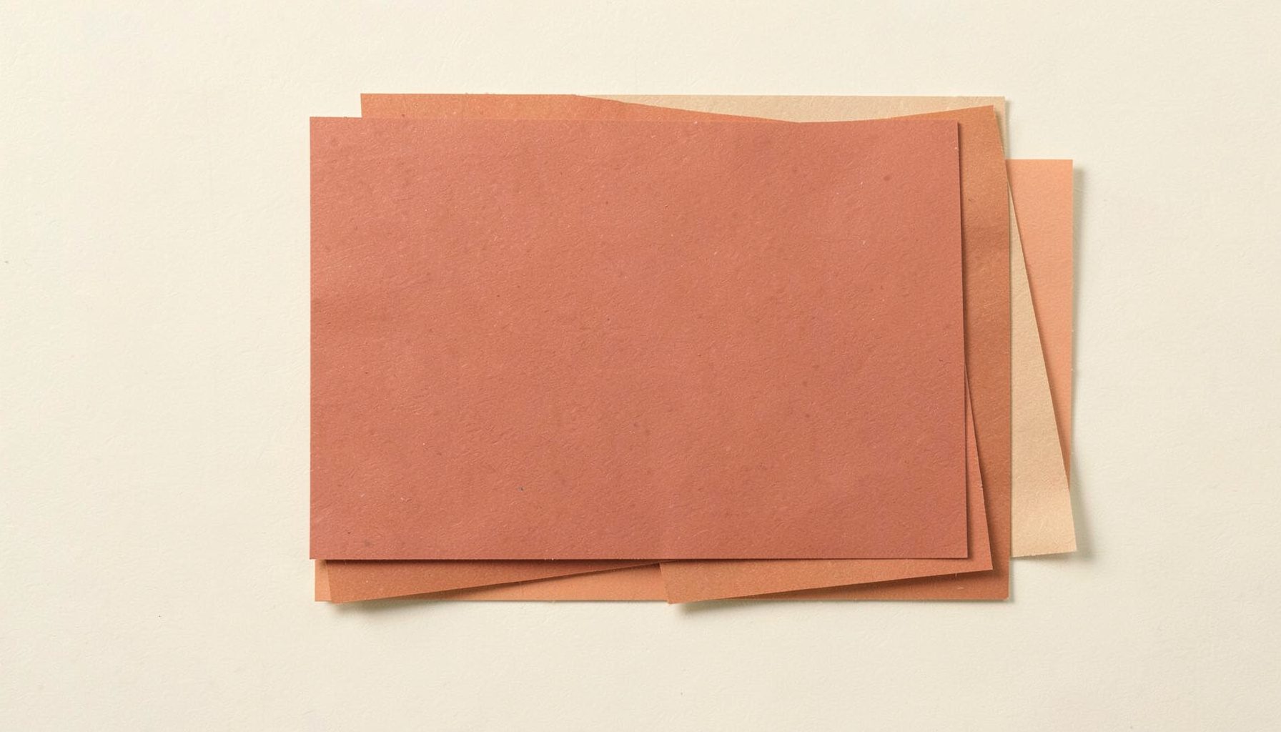 Paper cut-out rectangle in muted terracotta layered over a cream background, suggesting a window display.