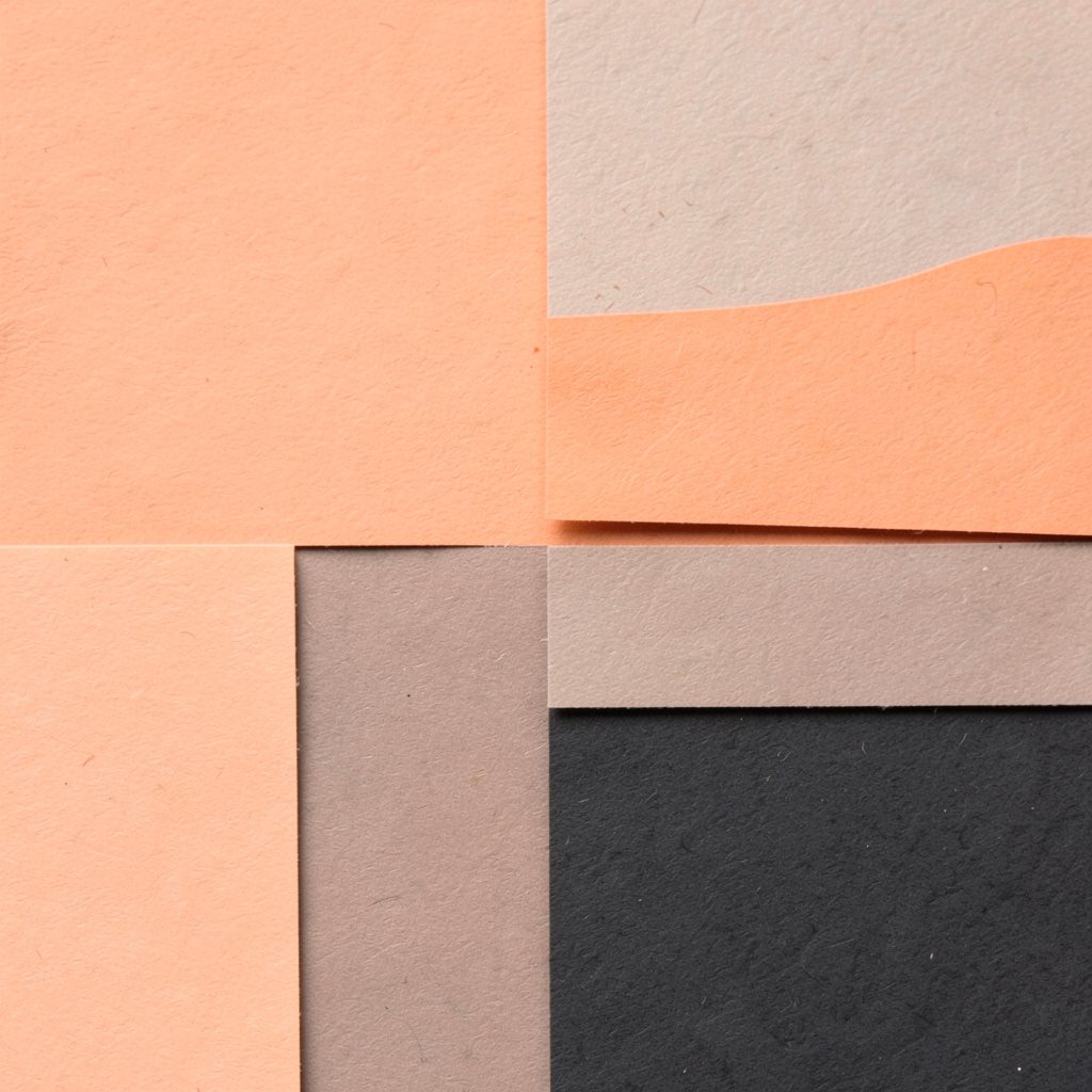 Square paper texture in warm peach and charcoal blocks.