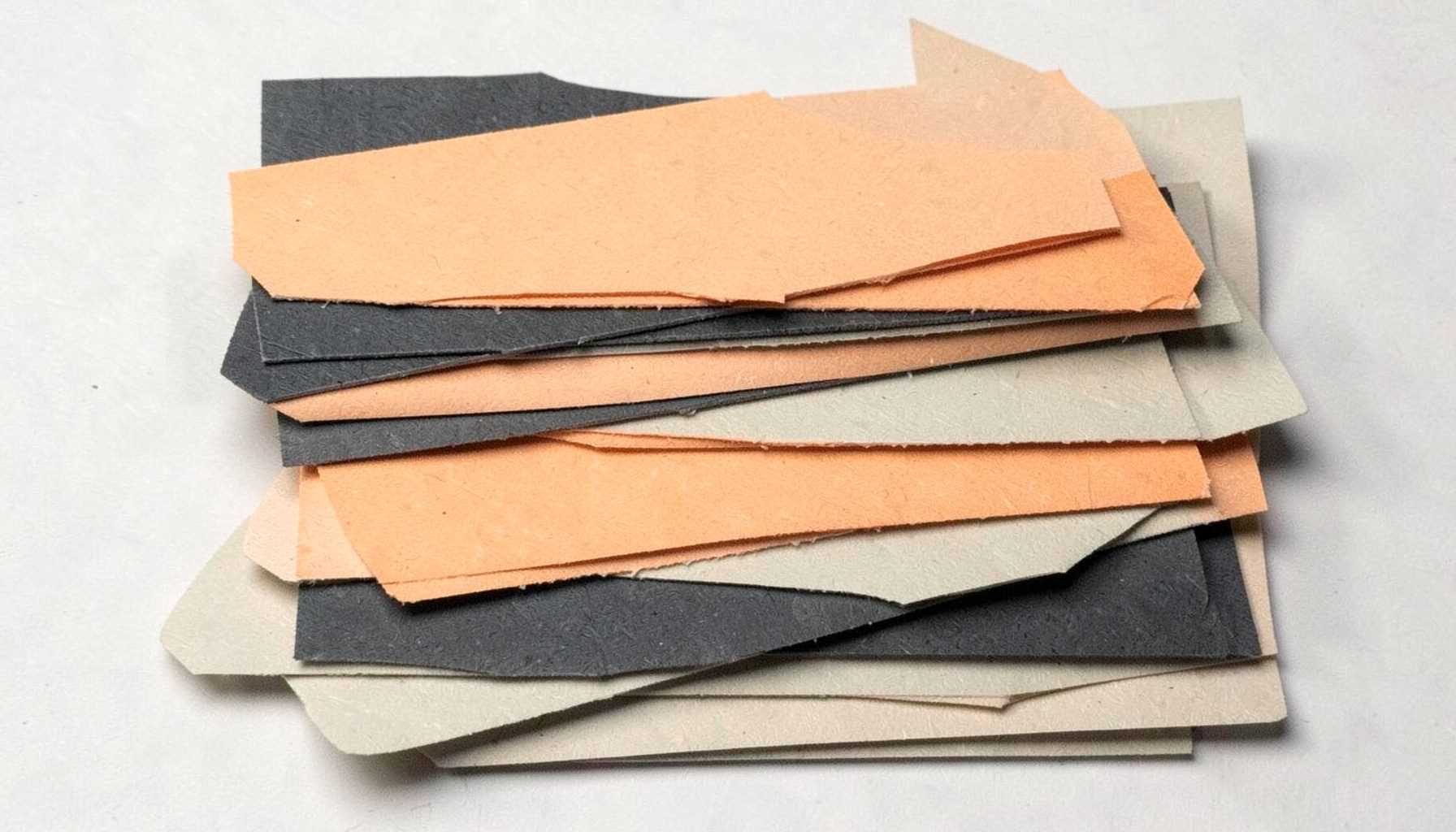 Stacked paper shapes in charcoal and warm beige, evoking stacked signage.